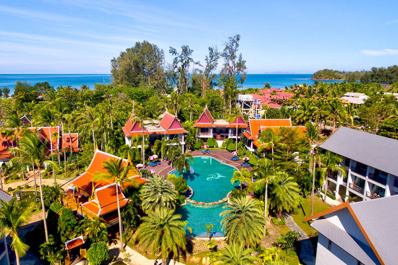 Tropikalny hotel z basenem i palmami nad brzegiem oceanu – widok z lotu ptaka.