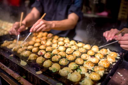 Kucharz obraca kulki takoyaki na specjalnej, gorącej patelni.