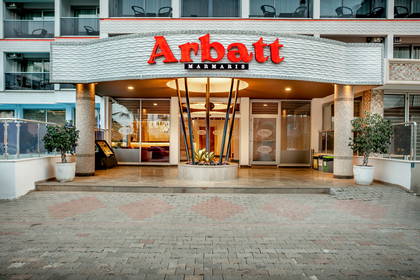 Nowoczesne wejście do hotelu Arbatt Marmaris z dużym, czerwonym szyldem nad szklanymi drzwiami.