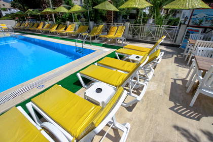 Rzędy żółtych leżaków i parasoli przy hotelowym basenie.