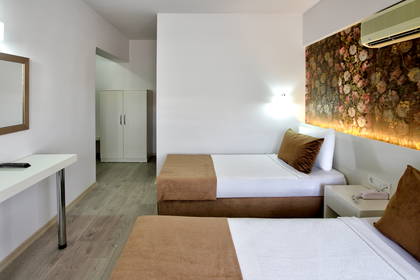 Nowoczesny pokój hotelowy z dwoma pojedynczymi łóżkami, białymi meblami i ścianą z podświetlanym motywem kwiatowym.