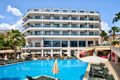 Goście opalają się na leżakach przy dużym basenie nowoczesnego hotelu.