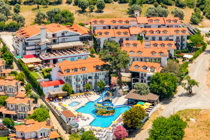 Ośrodek hotelowy z basenem i zjeżdżalnią, otoczony zielonymi wzgórzami. Widok z lotu ptaka.