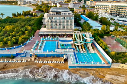 Widok z lotu ptaka na kompleks hotelowy z basenami i zjeżdżalniami wodnymi, tuż przy piaszczystej plaży.