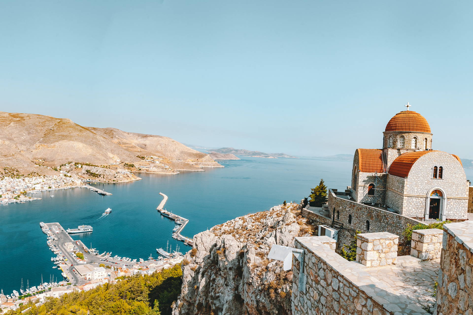 Widok na miasto portowe Symi w Grecji z górami i kościołem w tle.