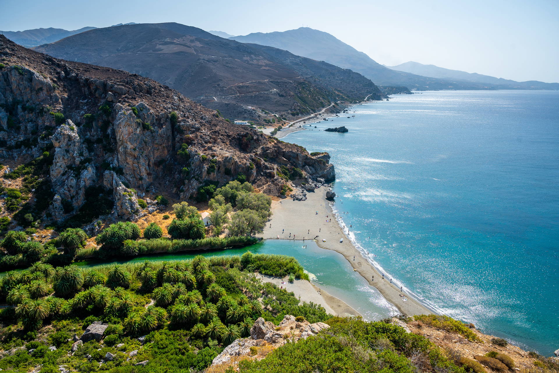 Plaża Preveli na Krecie z lotu ptaka. Zielona rzeka płynie przez gaj palmowy i wpada do turkusowego morza.