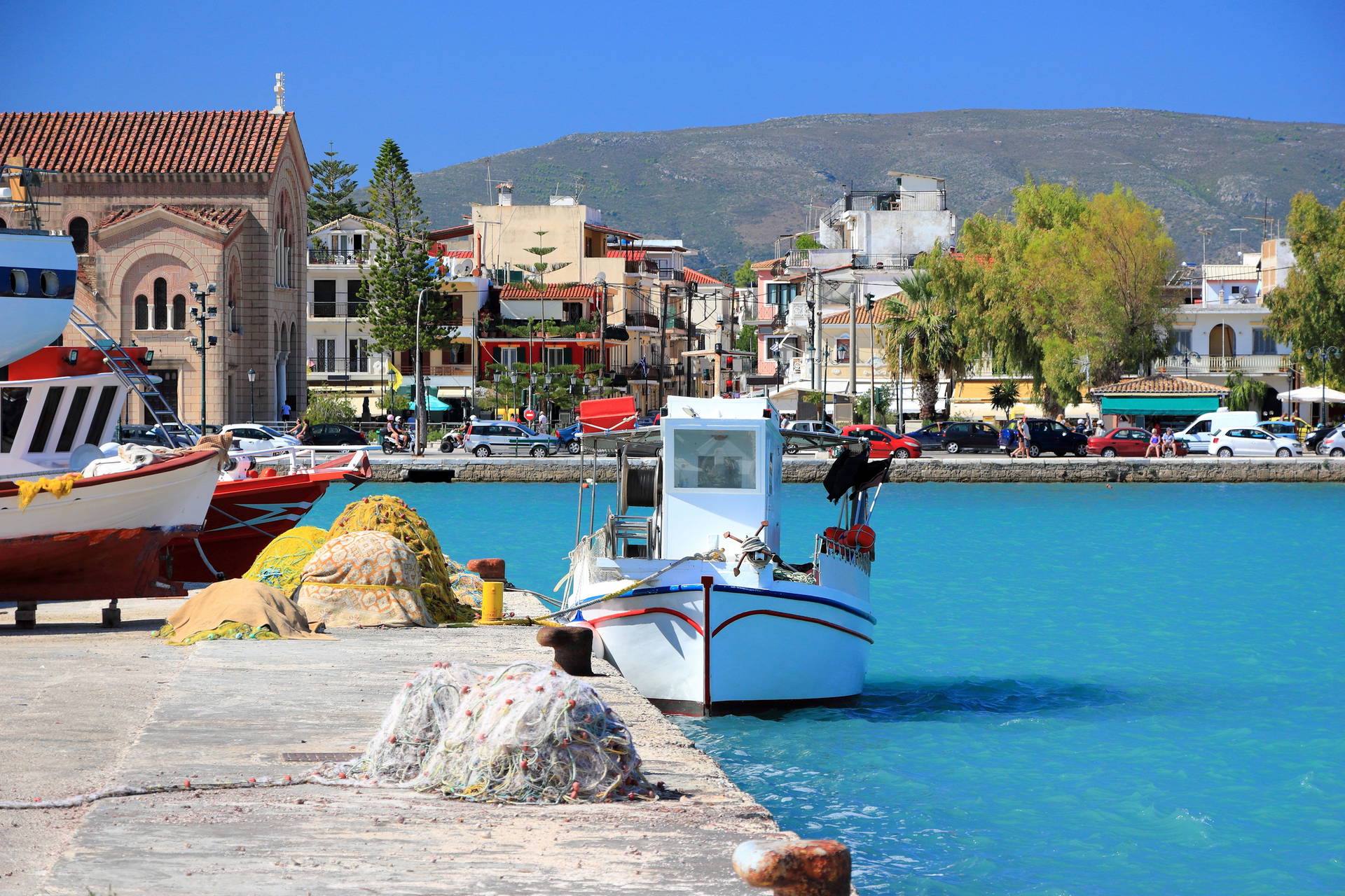 Kolorowy port w Egina, Grecja. W tle łodzie, sieci rybackie i budynki.