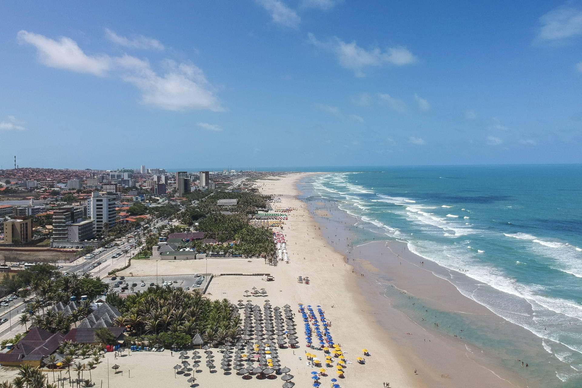 Plaża w Natal, Brazylia widziana z góry. Na piasku widać parasole, ludzi i fale oceanu.