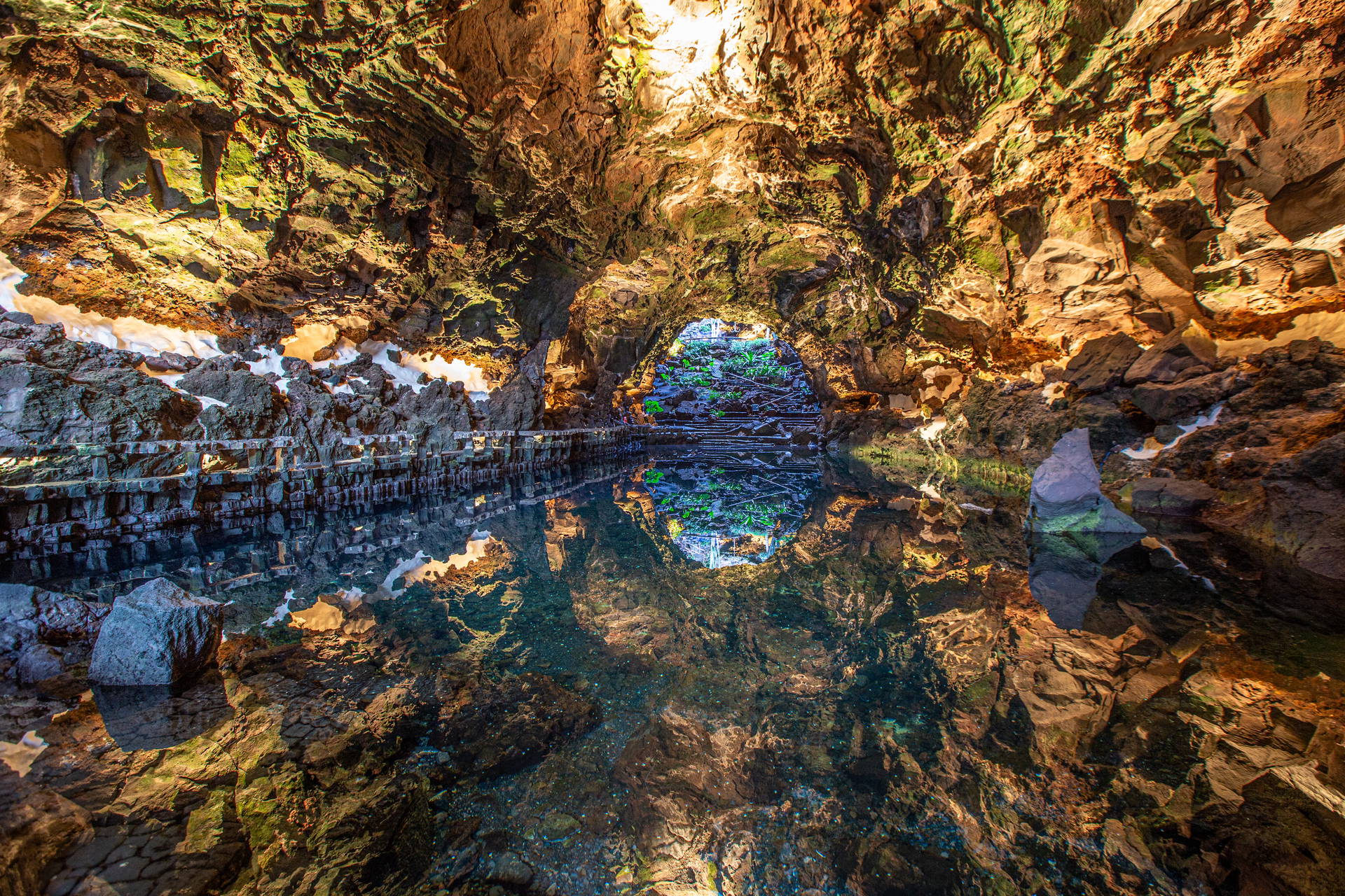Oświetlona jaskinia wulkaniczna Jameos del Agua z podziemnym jeziorem, które odbija skaliste sklepienie.