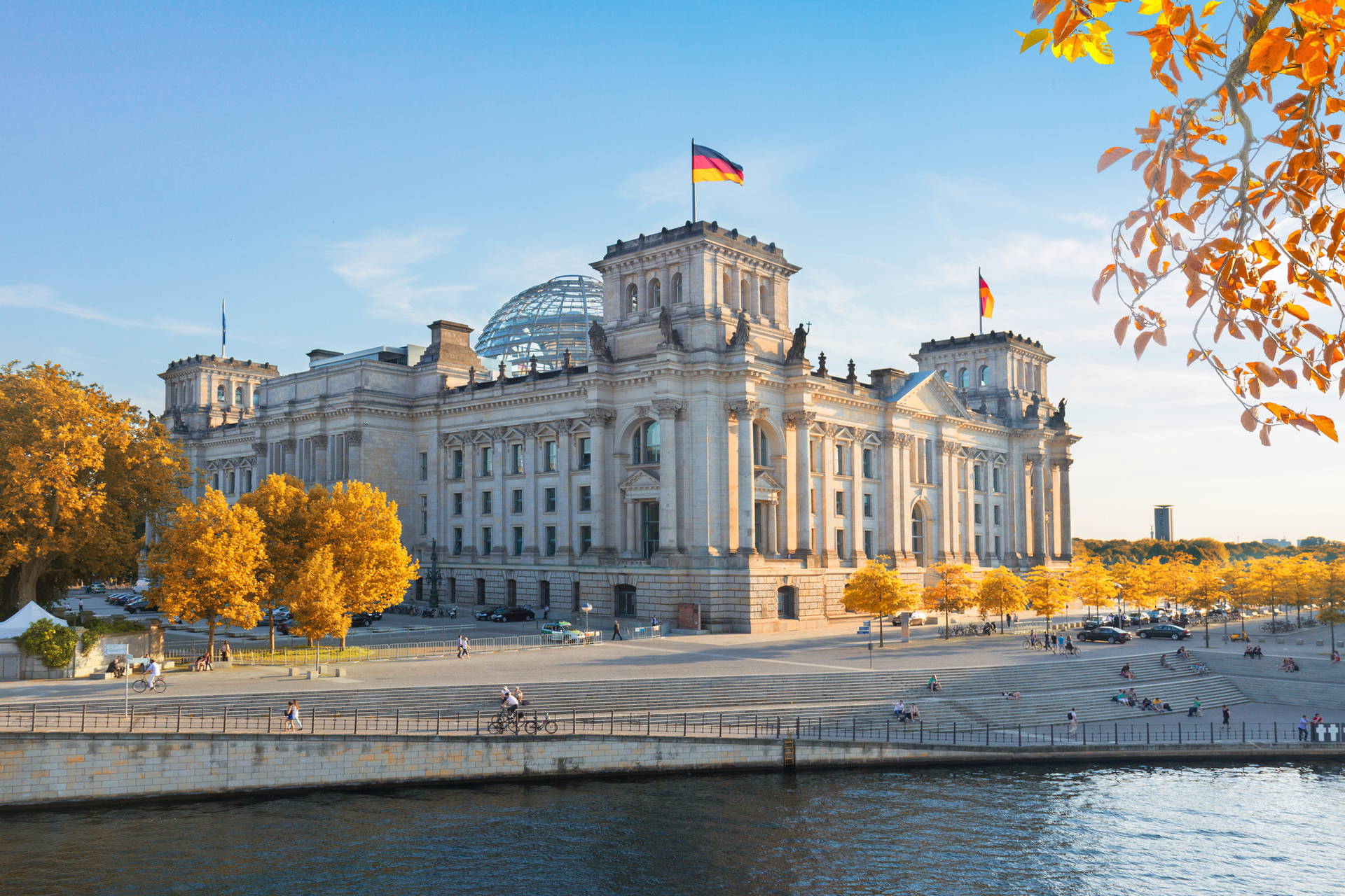 Reichstag w Berlinie z niemiecką flagą na dachu.