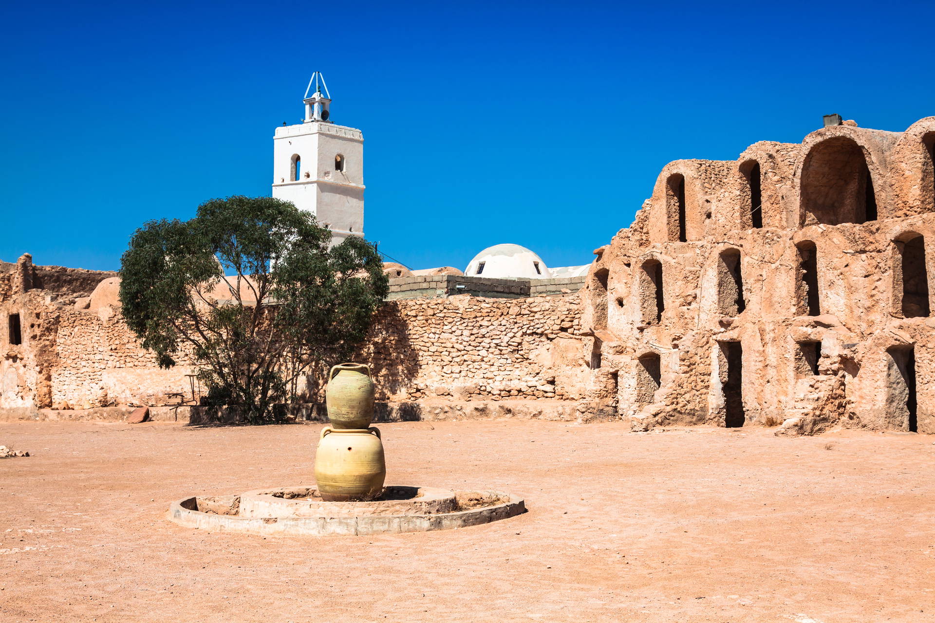 Dziedziniec Ksar Ouled Soltane w Tunezji z wieżą meczetu i amforami.