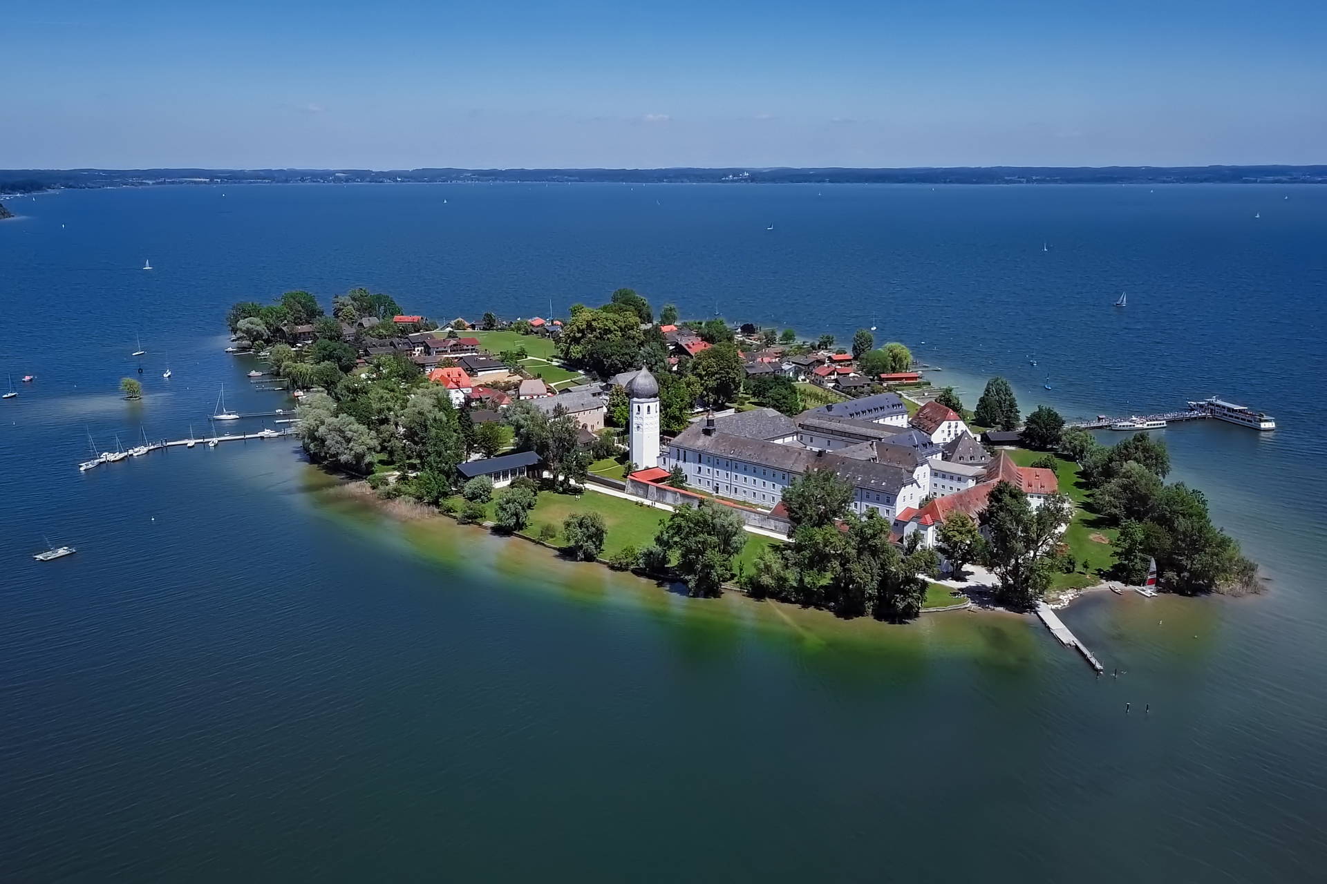 Widok z lotu ptaka na wyspę Frauenchiemsee na jeziorze Chiemsee, na której widać klasztor, domy i drzewa.
