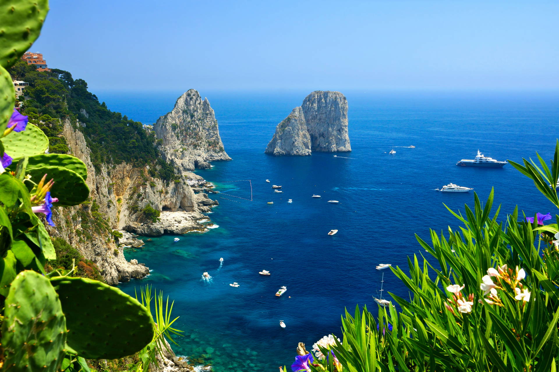 Formacje skalne Faraglioni na Capri, łodzie i jachty na morzu.
