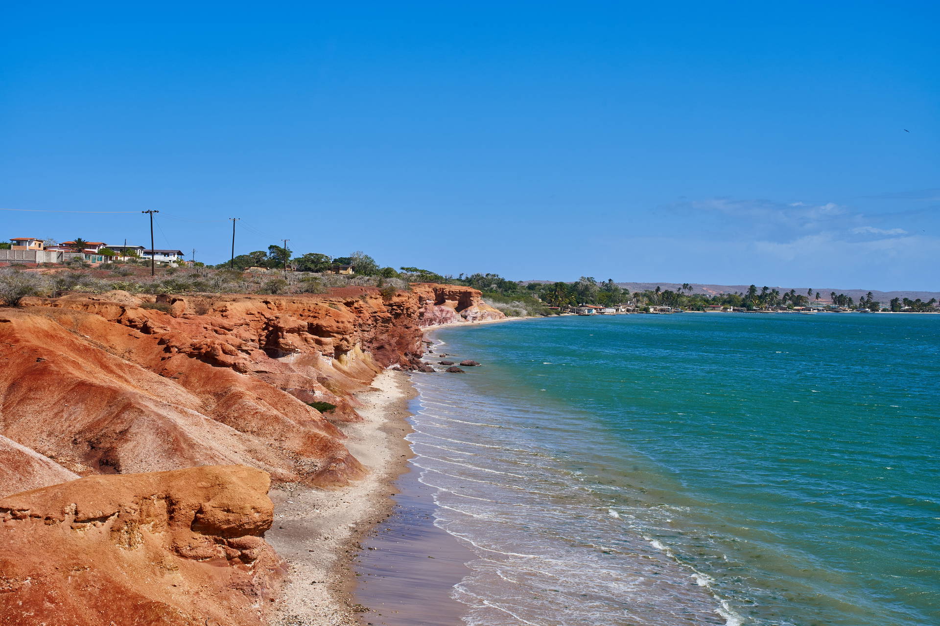 Czerwone klify schodzące do piaszczystej plaży i turkusowego morza na wybrzeżu Madagaskaru.