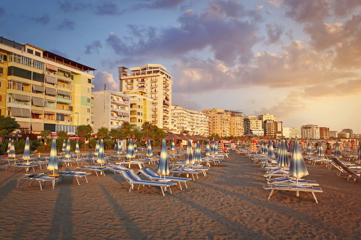 Zachód słońca na plaży w Durrës. W tle hoteli widać rzędy pustych leżaków i parasoli.