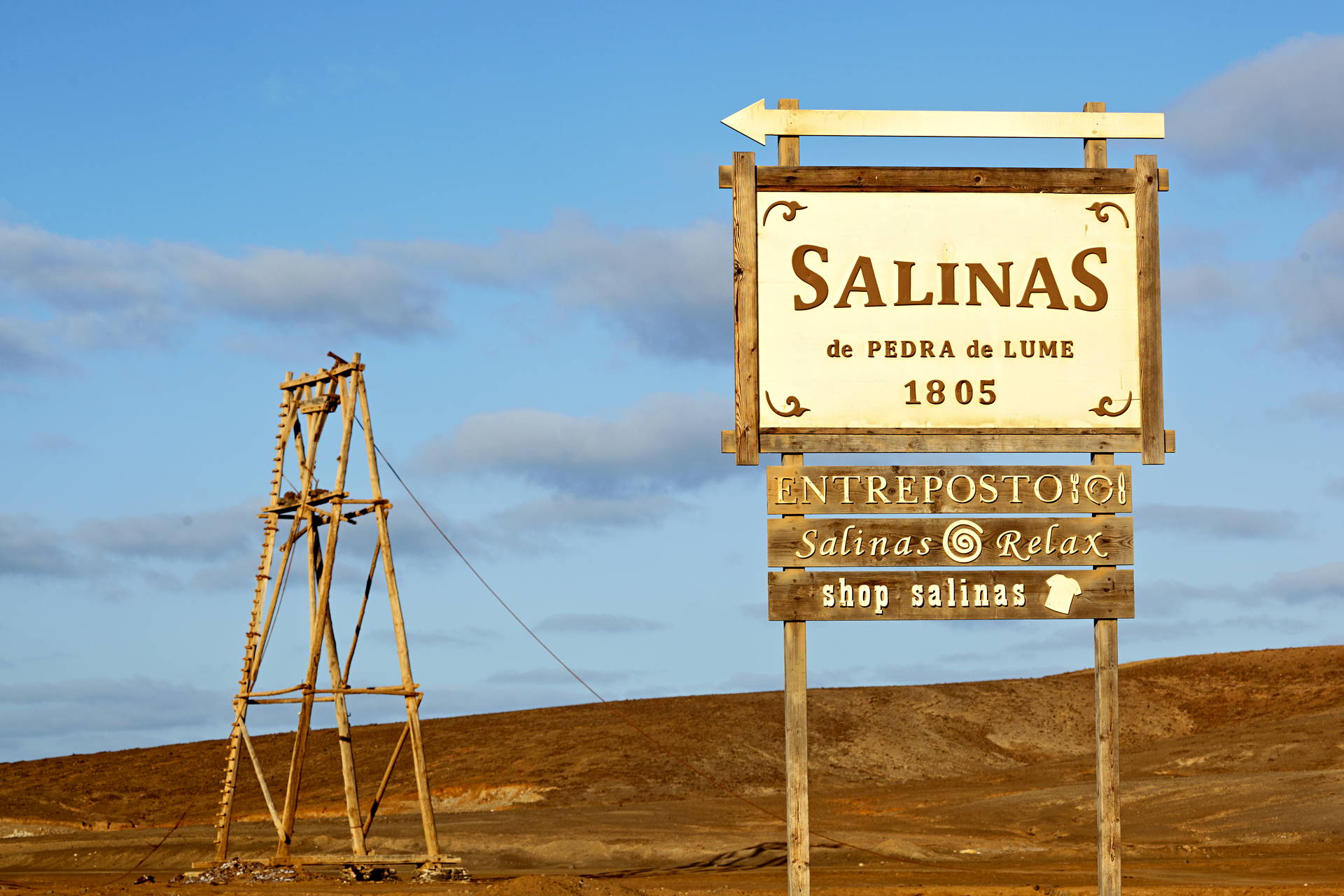 Drewniany znak z napisem "Salinas de Pedra de Lume 1805" na tle wulkanicznego krajobrazu.