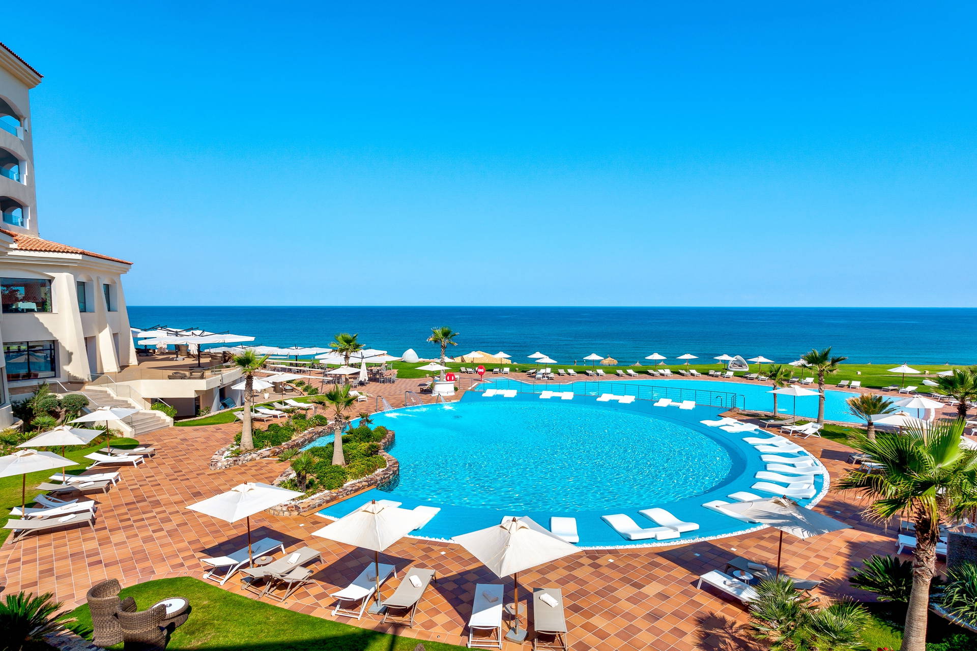 Basen hotelowy z widokiem na morze i błękitne niebo.