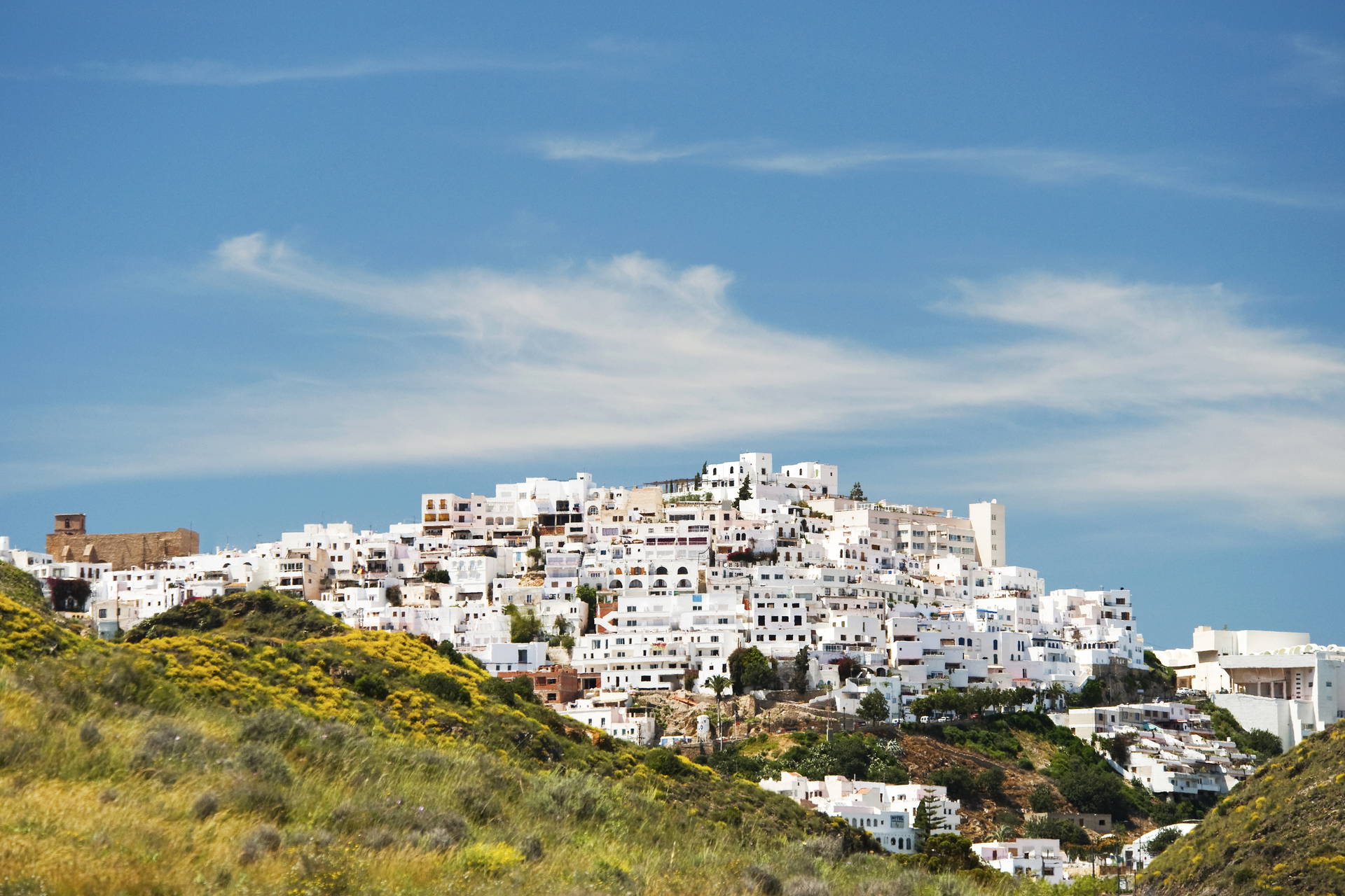 Wzgórze z białą zabudową pod błękitnym niebem.