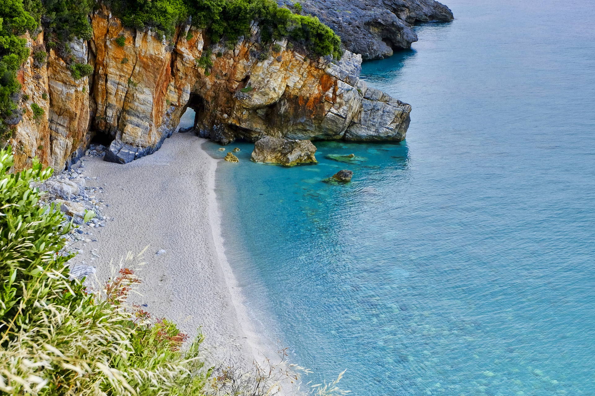 Plaża z klifami i błękitną wodą widziana z góry.