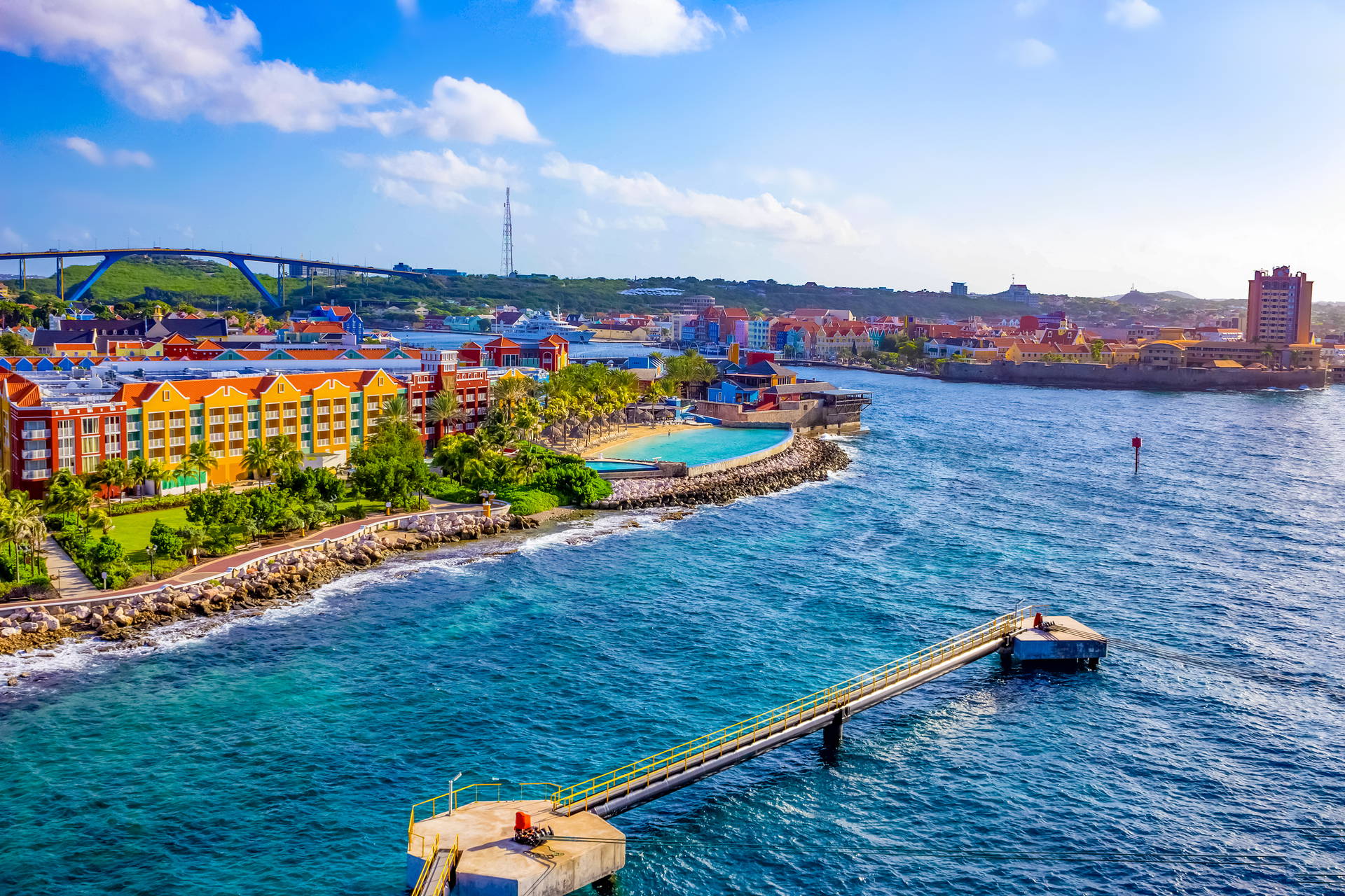 Kolorowa zabudowa nabrzeża w Willemstad na Curaçao, z mostem Królowej Juliany w tle.