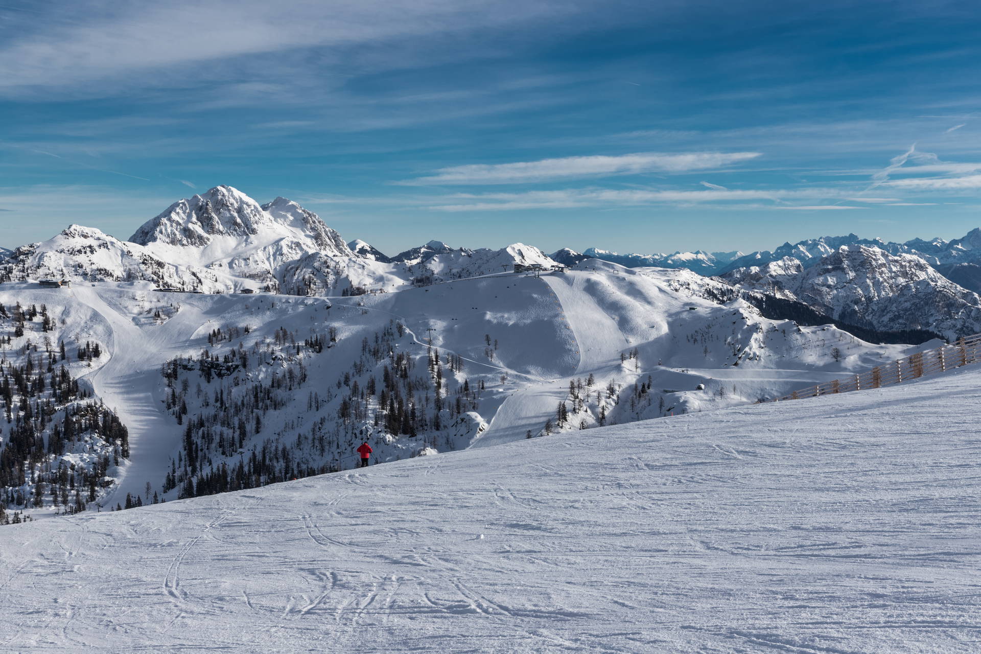 Ośnieżony krajobraz górski ze snowboardzistą na stoku.