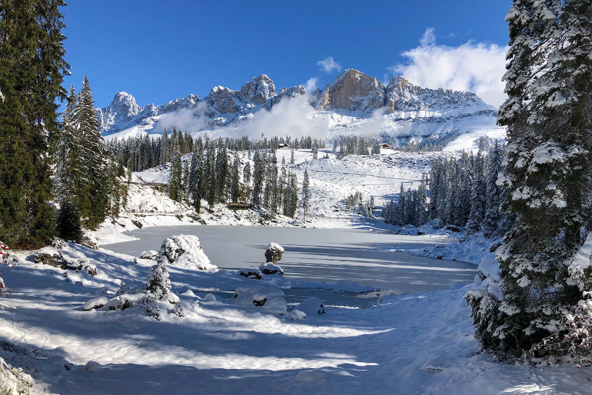 Zamarznięte jezioro Carezza i ośnieżone Dolomity zimą.