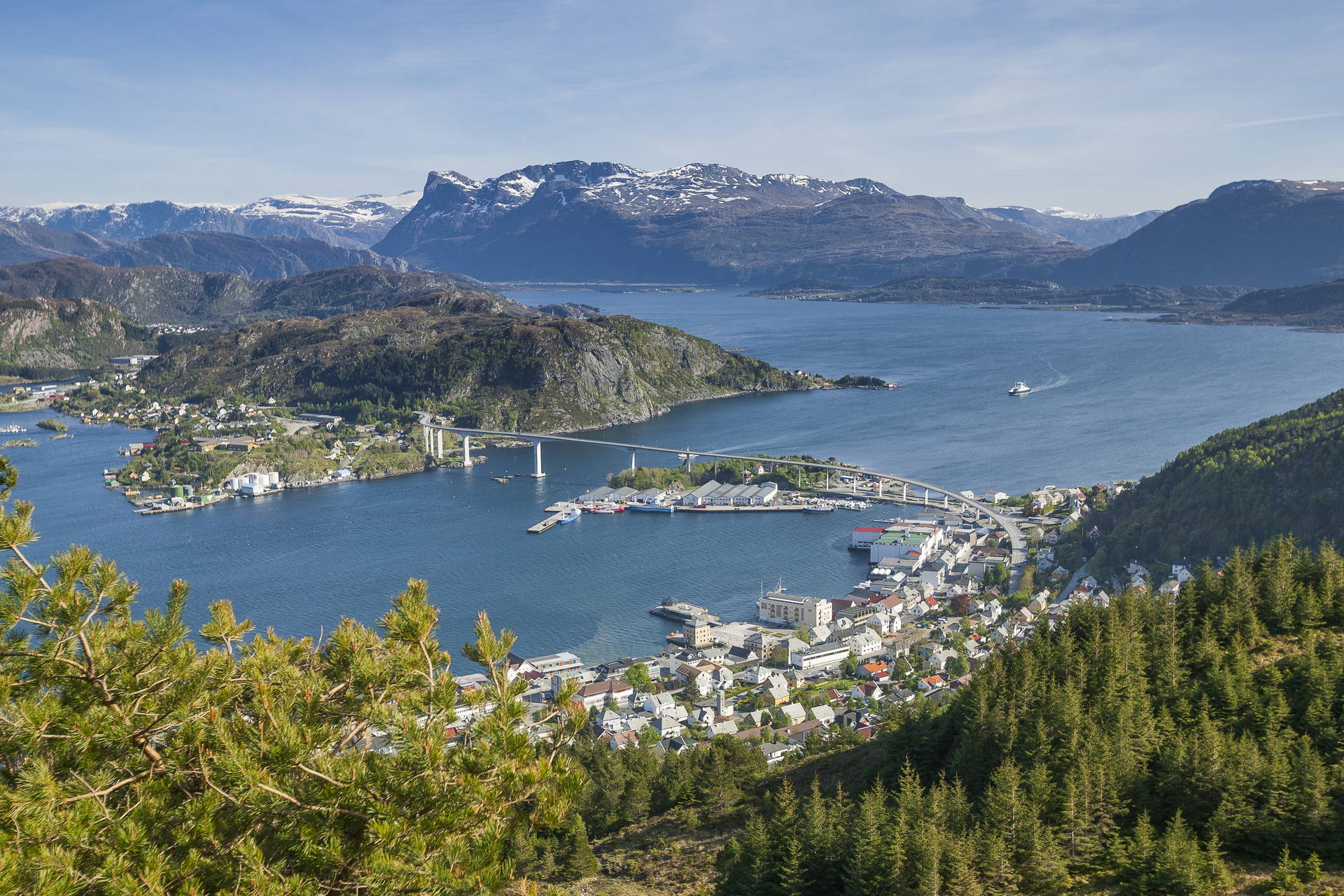 Norweskie miasto Måløy, położone nad fiordem. Widok z góry na most i ośnieżone szczyty w tle.
