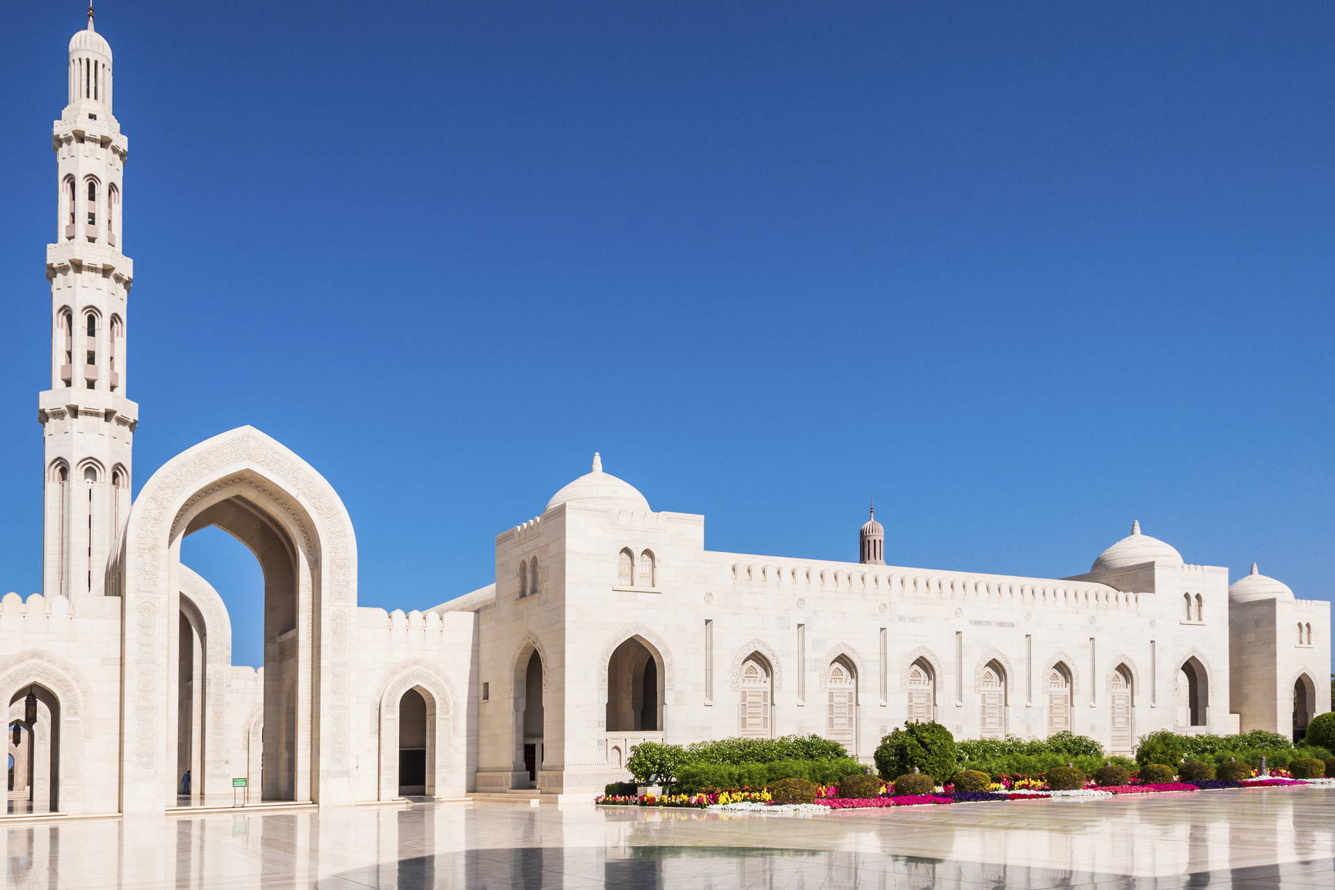 Biały meczet z wieżą na tle błękitnego nieba.