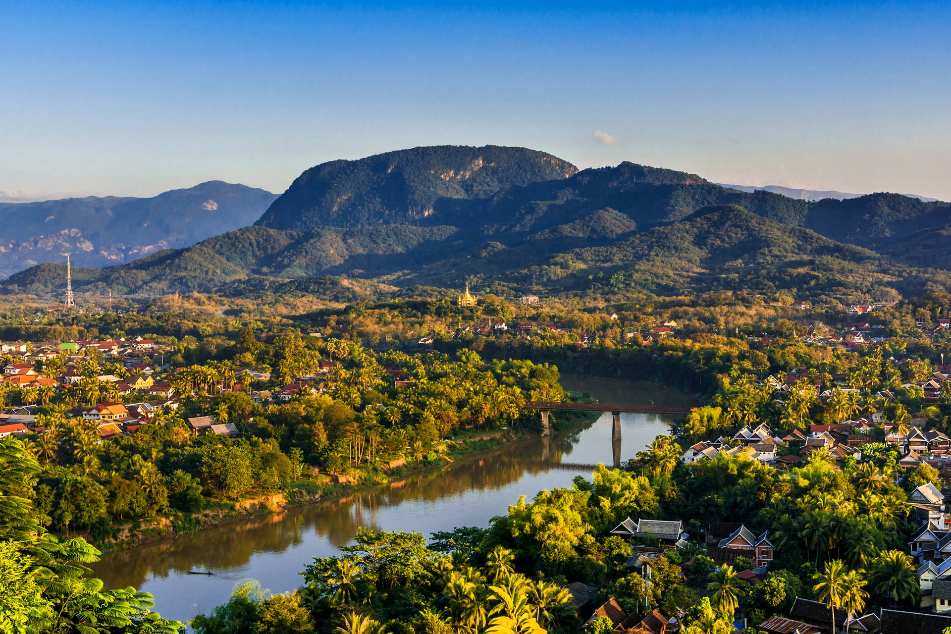 Krajobraz Luang Prabang z rzeką, mostem i górami w tle.
