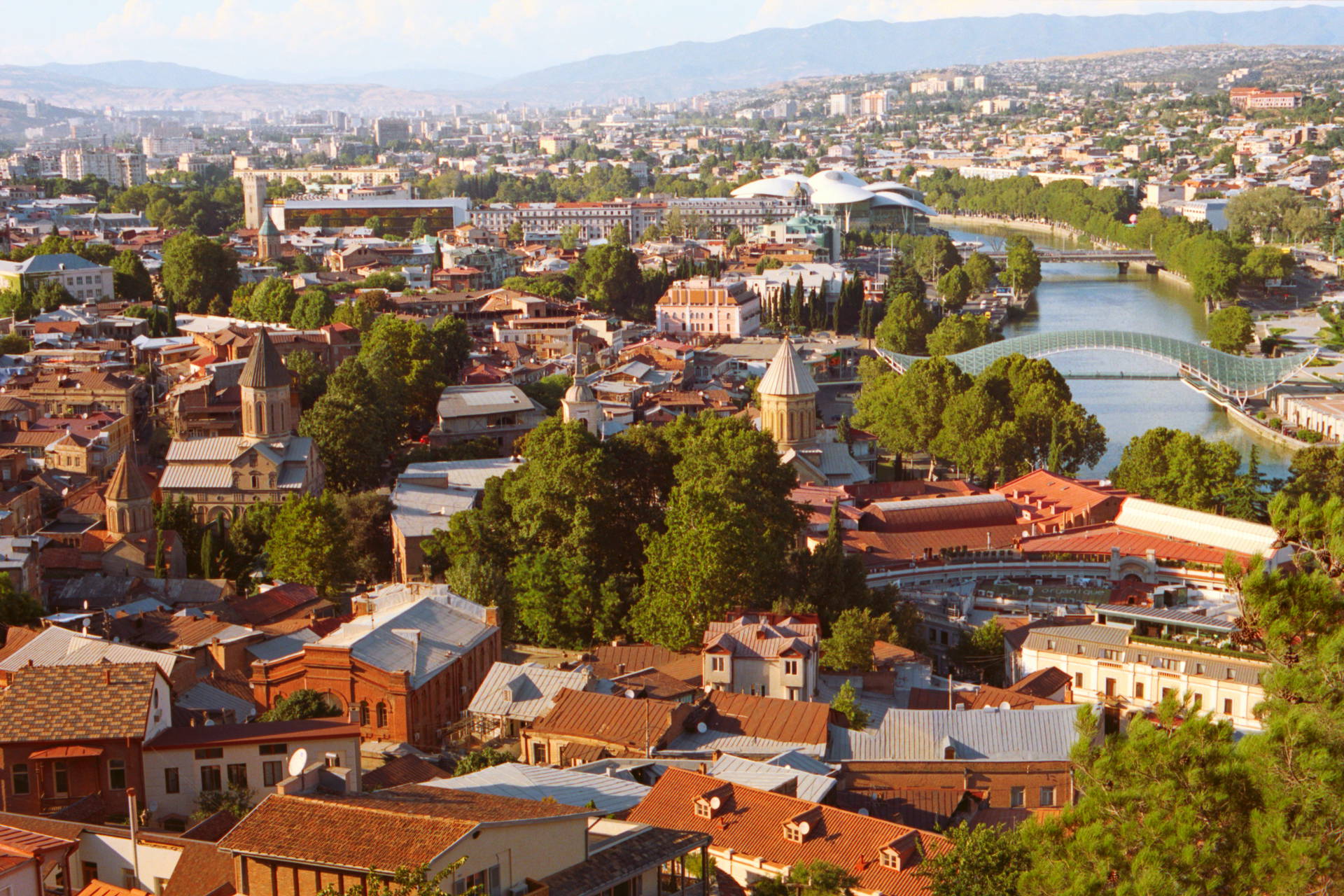 Panorama Tbilisi z widokiem na miasto, rzekę i góry.