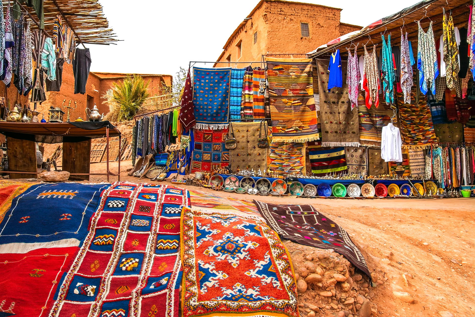 Targ w Marrakeszu z dywanami i ubraniami.