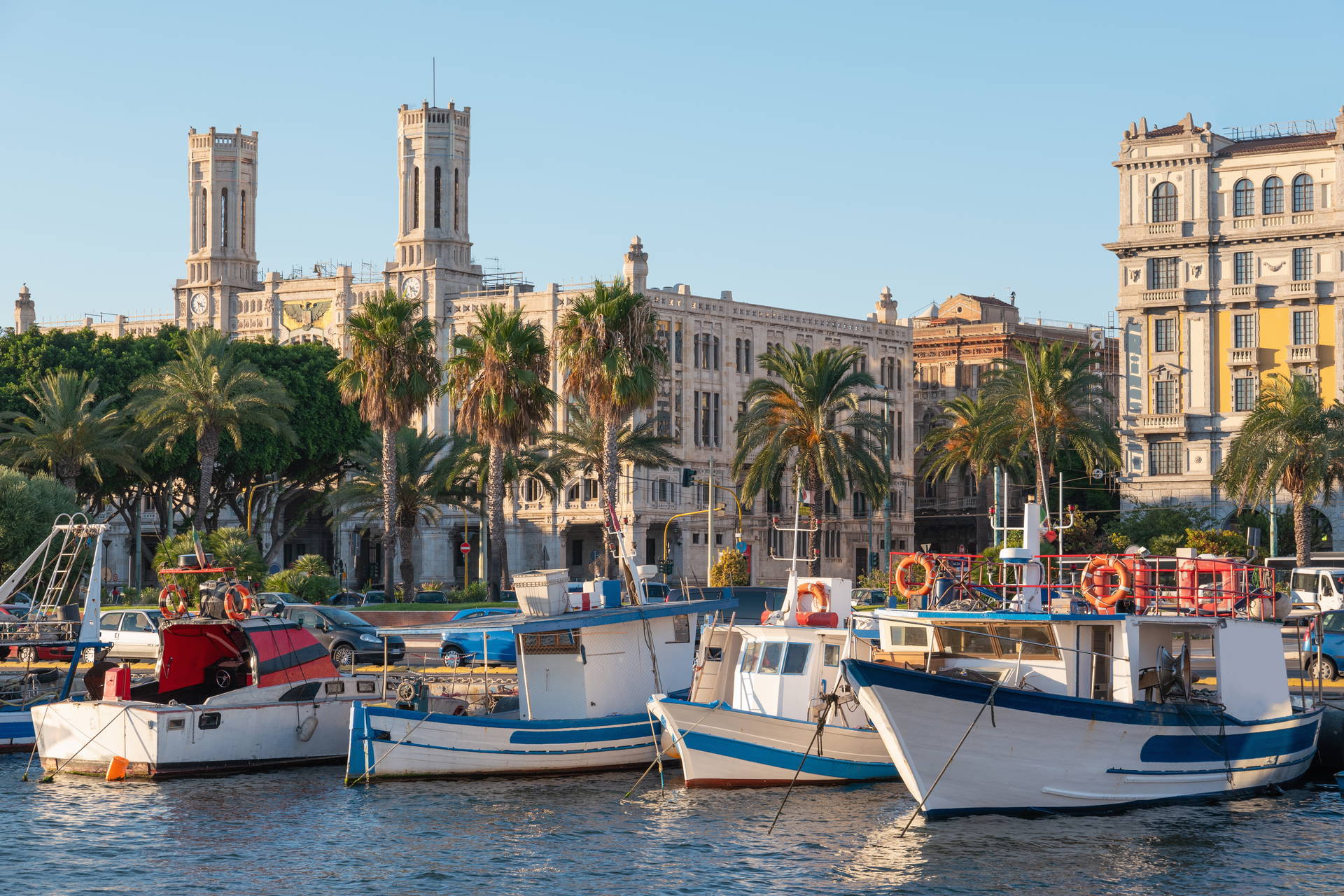 Port w Cagliari z łodziami i budynek regionalnego parlamentu w tle.
