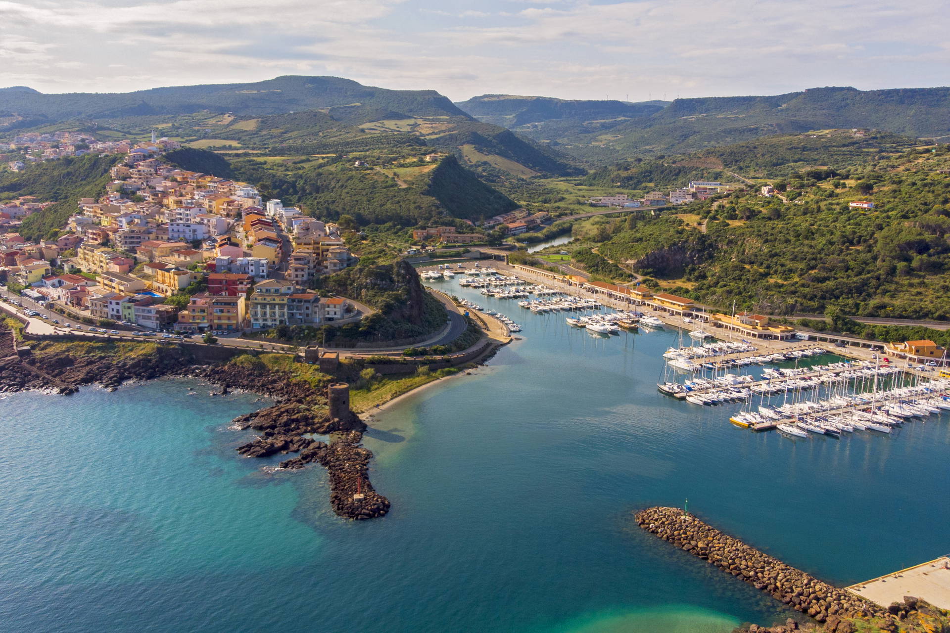 Widok z lotu ptaka na miasteczko Castelsardo na Sardynii. Widoczne kolorowe budynki i port jachtowy.