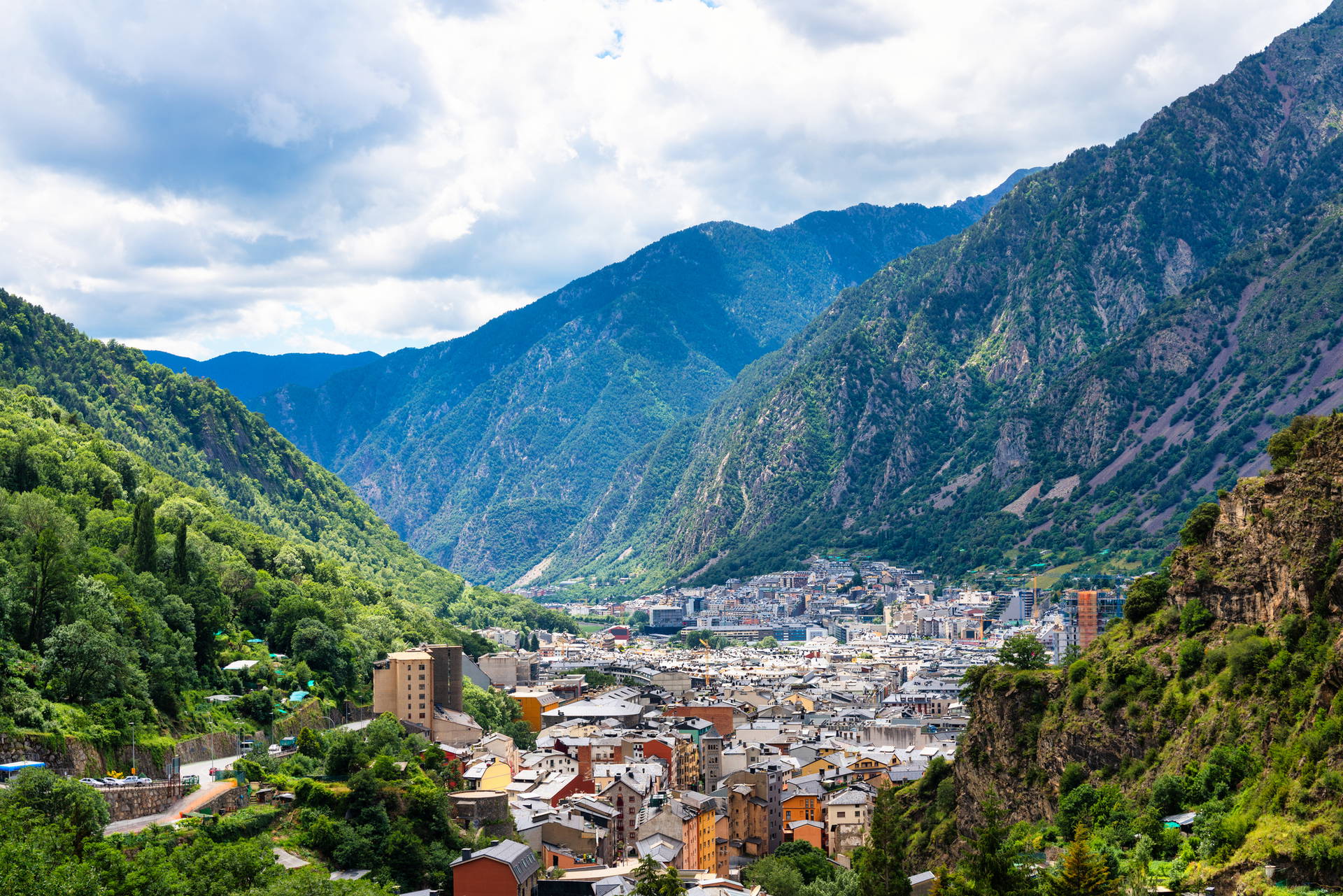 Widok na miasto Andorra la Vella, położone w dolinie otoczonej wysokimi, zielonymi górami.