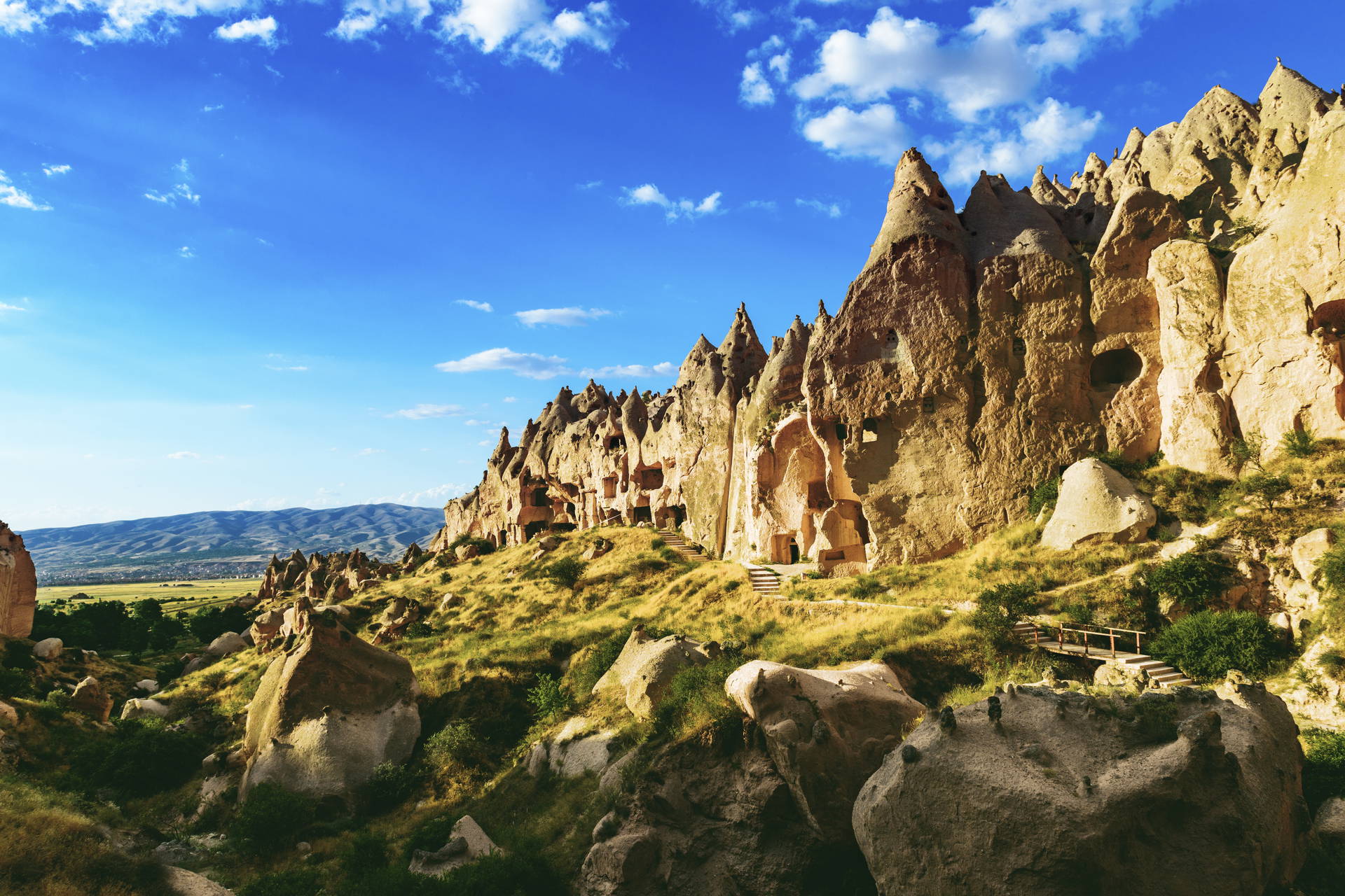 Formacje skalne w Kapadocji, Turcja, na tle błękitnego nieba z chmurami.