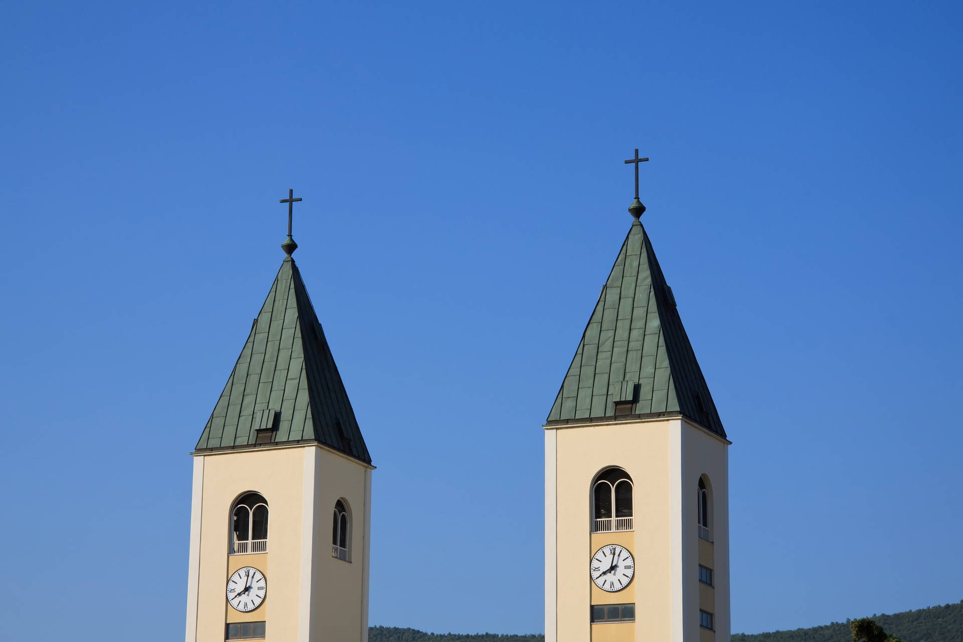 Dwie wieże kościelne z zegarami na tle błękitnego nieba.