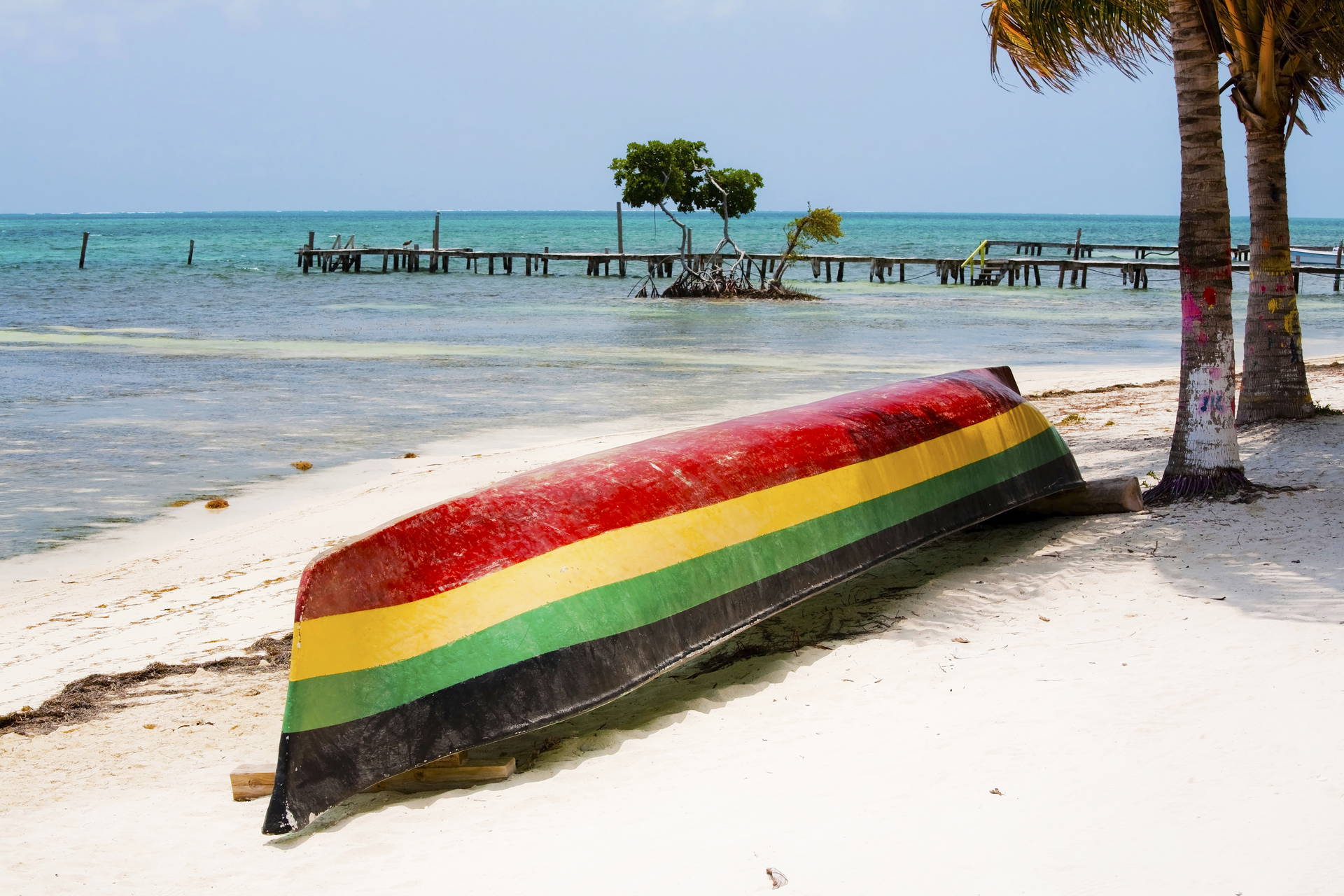 Kolorowa łódź na plaży, w tle pomost.