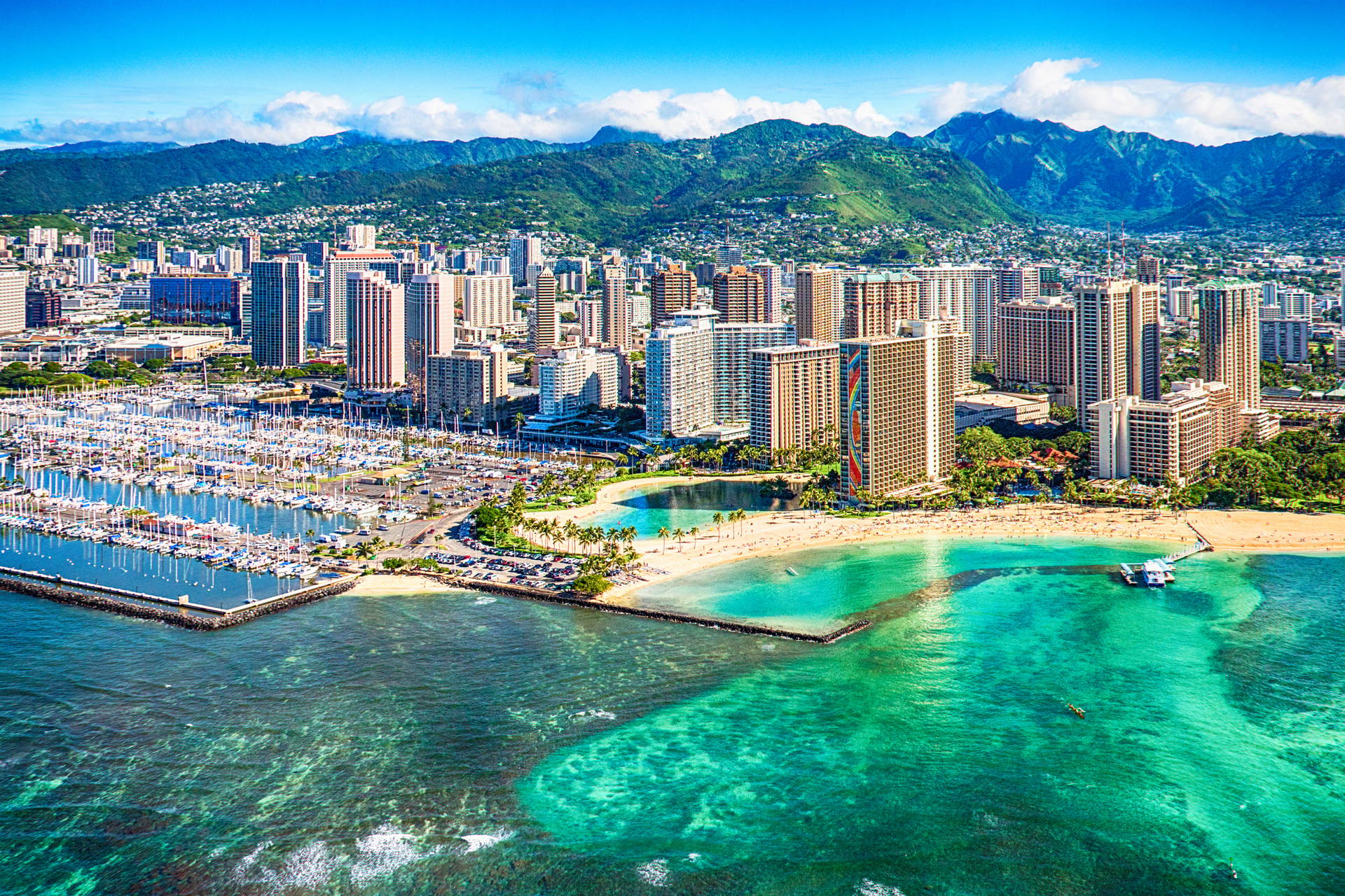 Widok z lotu ptaka na Honolulu na Hawajach. Widać przystań, plażę, budynki i góry w tle.