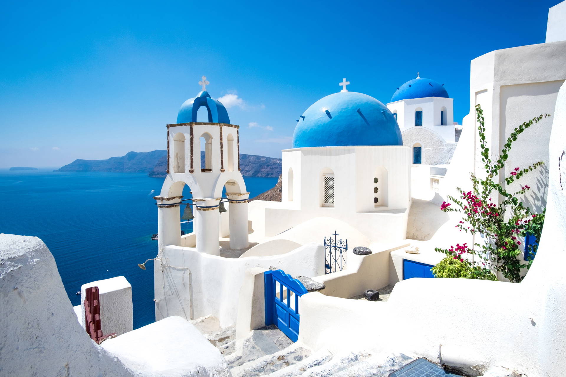 Santorini, Grecja. Białe budynki z niebieskimi kopułami na tle morza.