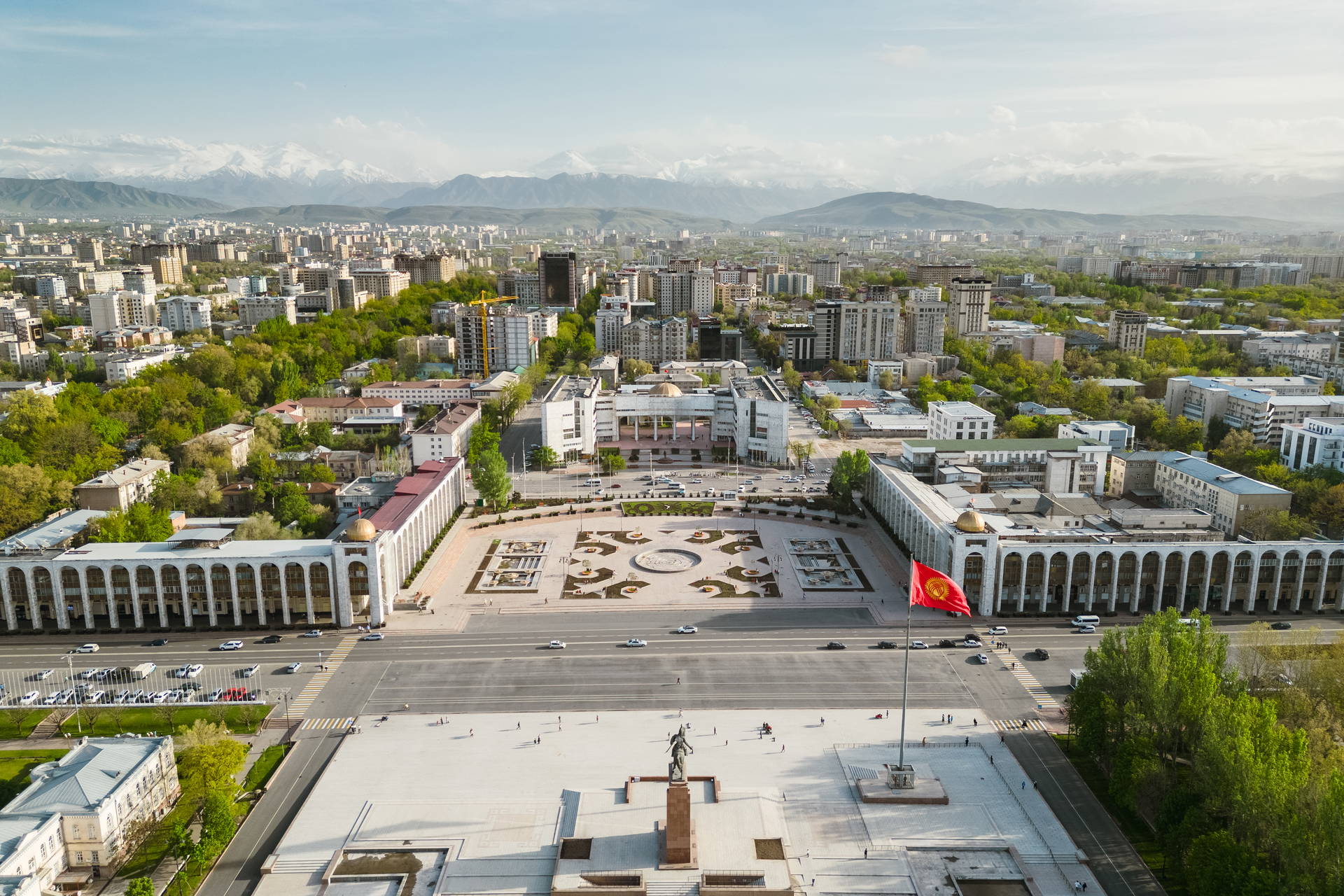 Plac Ala-Too w Biszkeku z lotu ptaka. Na pierwszym planie widać flagę Kirgistanu, a w tle panoramę miasta i góry.