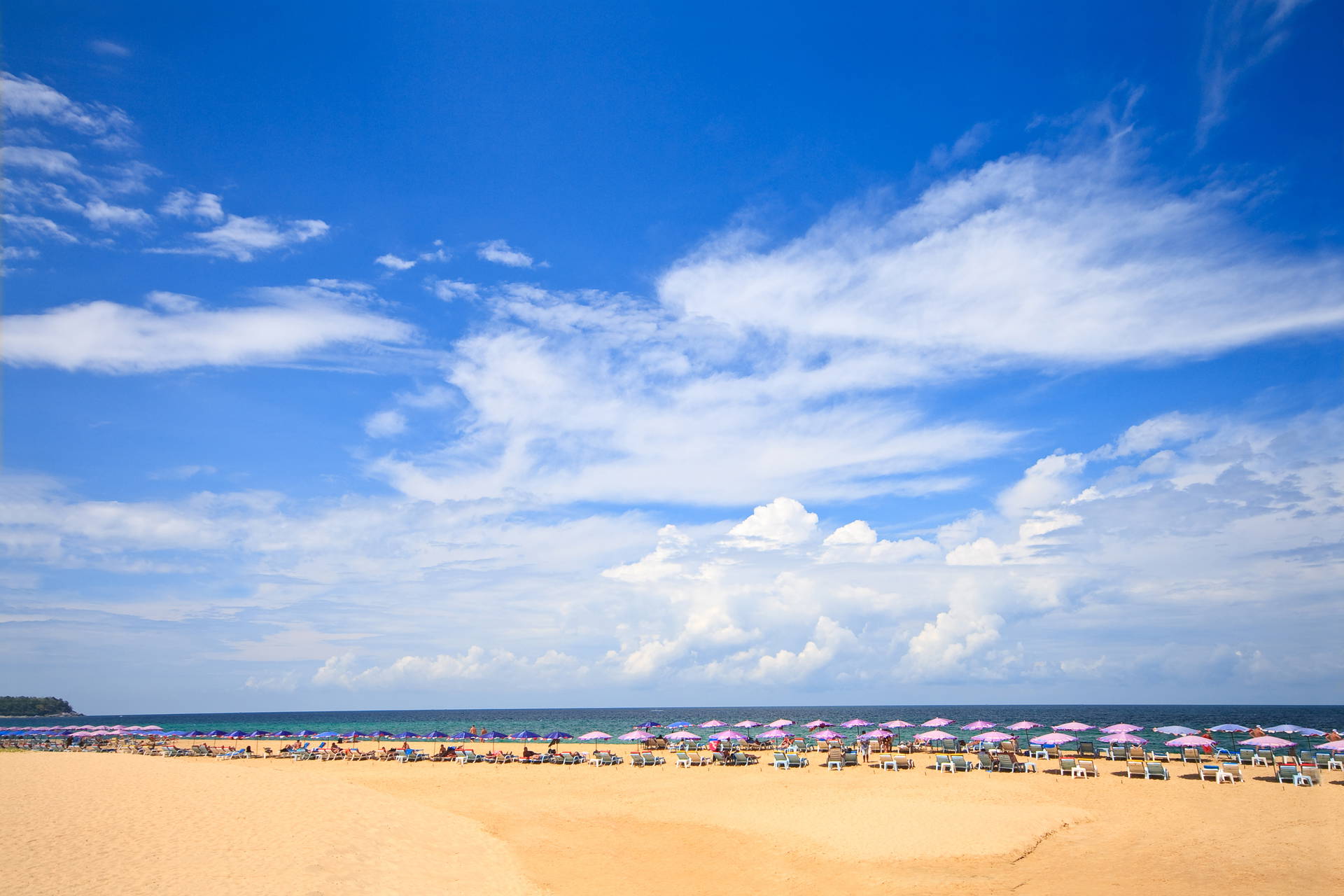 Plaża z parasolami i błękitne niebo w tle.