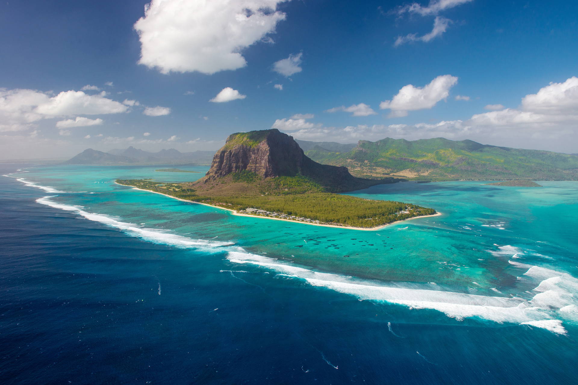 Le Morne Brabant na Mauritiusie widziany z lotu ptaka. Wokół lazurowa woda i białe chmury.