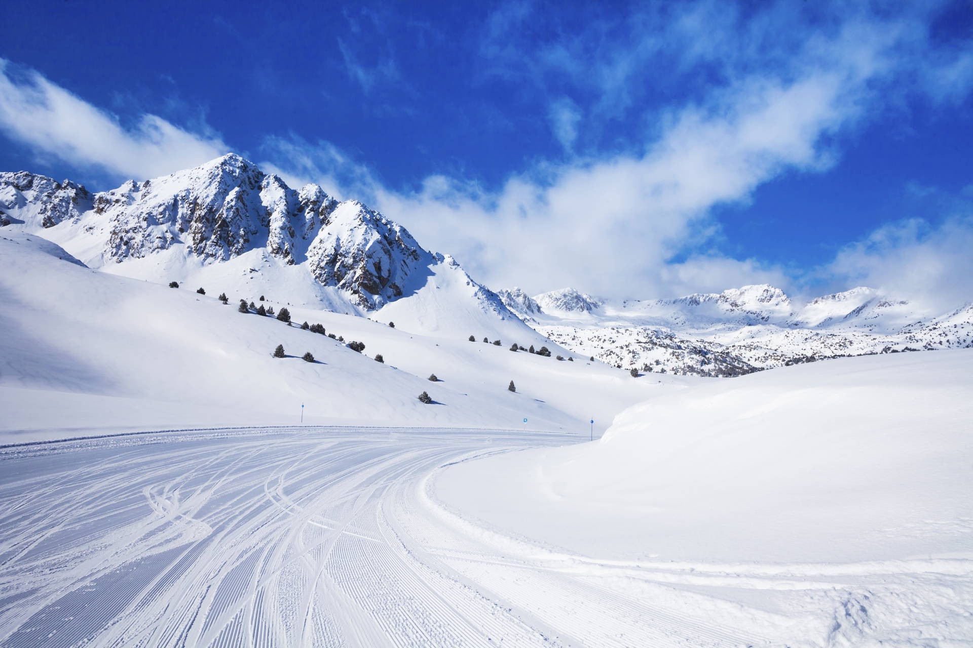 Zimowy krajobraz górski. Widok na ośnieżone szczyty i trasę narciarską.