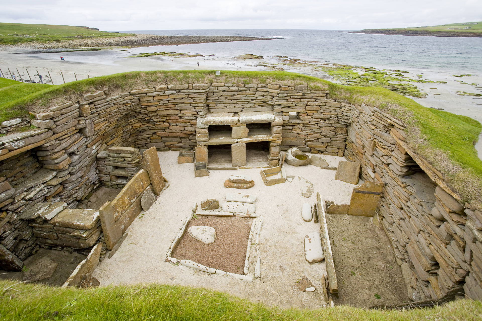 Wnętrze kamiennego domu z meblami w neolitycznej osadzie Skara Brae, położonej nad brzegiem morza.