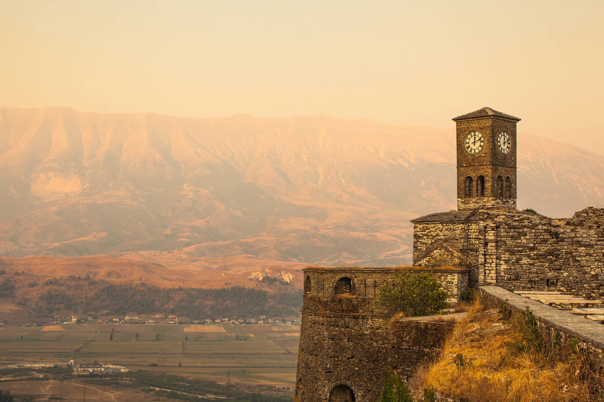 Kamienna wieża zegarowa w Gjirokastrze z widokiem na góry.