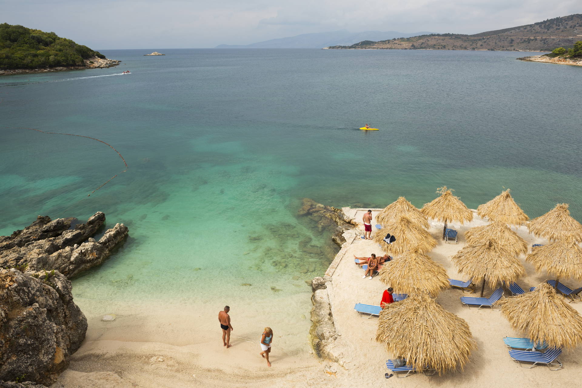 Plaża Ksamil w Albanii widziana z góry. Na piasku widać ludzi i parasole.
