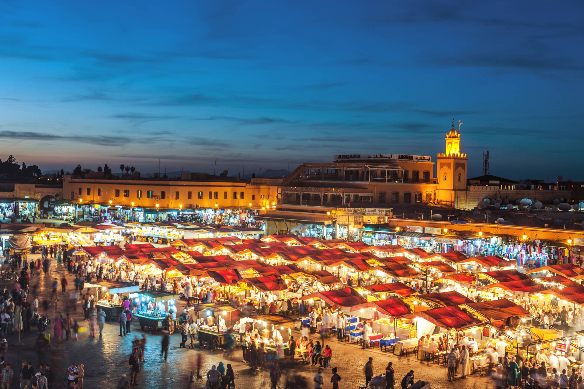 Nocny widok na plac Jemaa el-Fna w Marrakeszu, wypełniony straganami i tłumem ludzi.