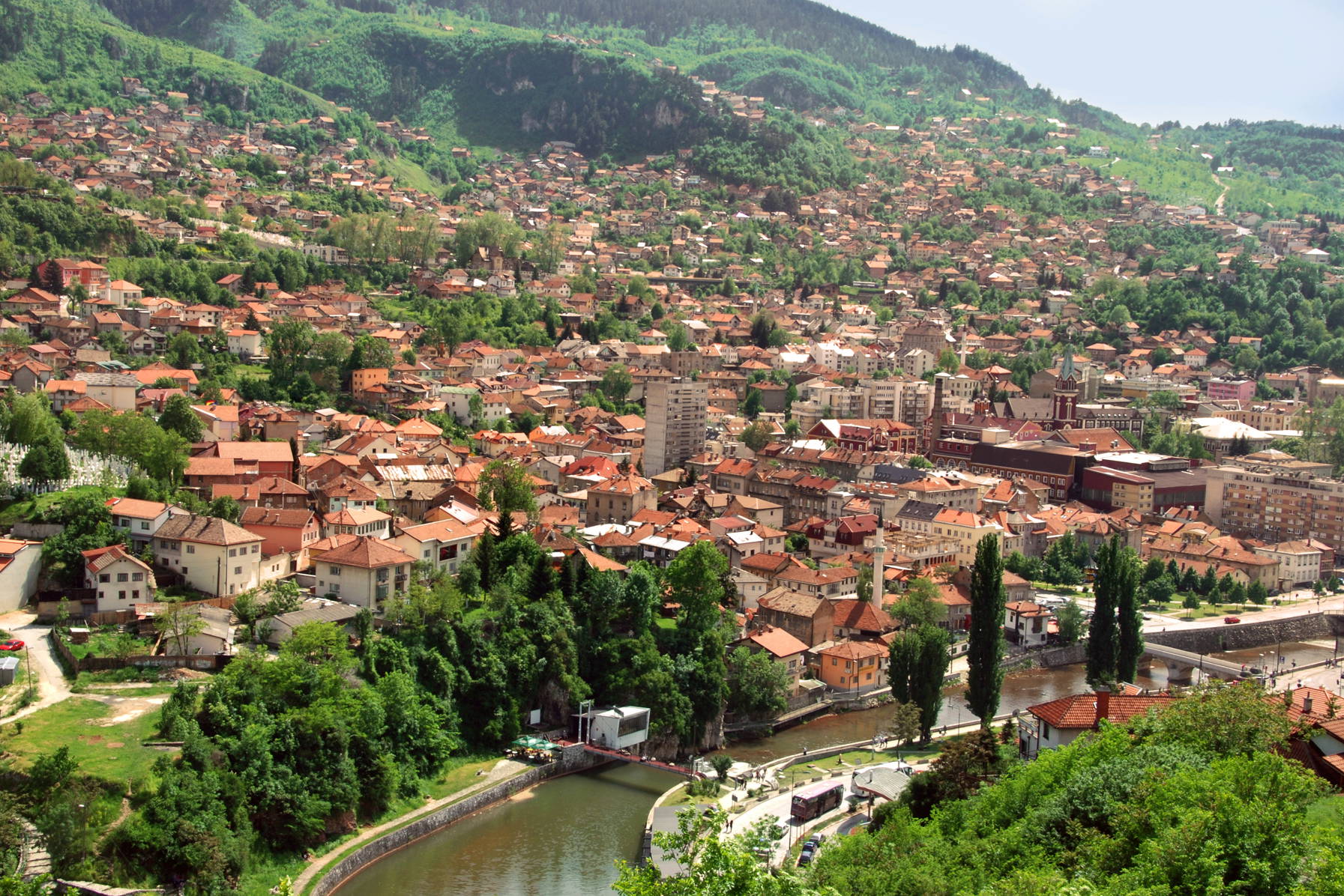 Widok na Travnik, miasto w Bośni i Hercegowinie z rzeką i budynkami o czerwonych dachach.