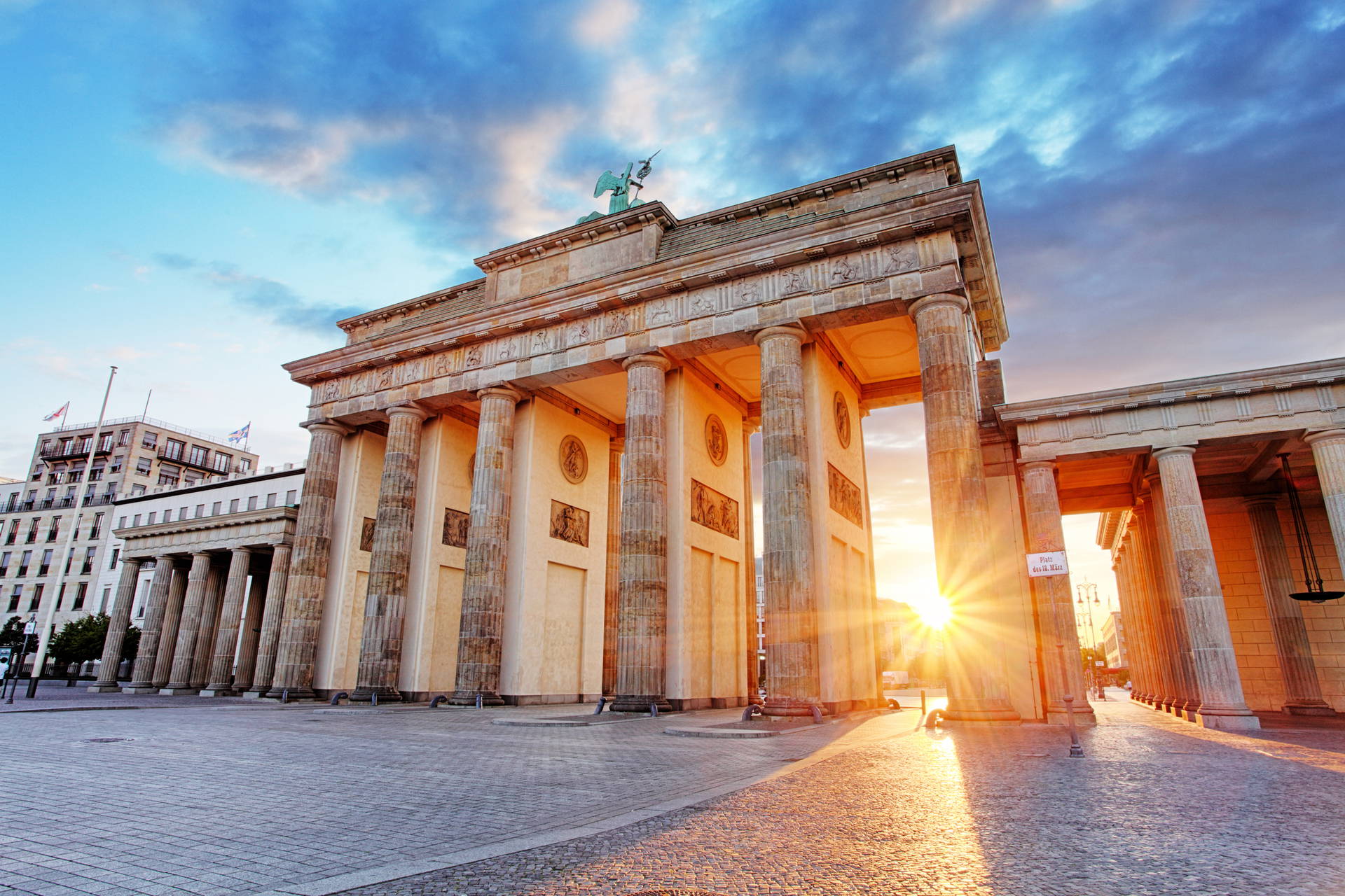 Brama Brandenburska w Berlinie w promieniach wschodzącego słońca.