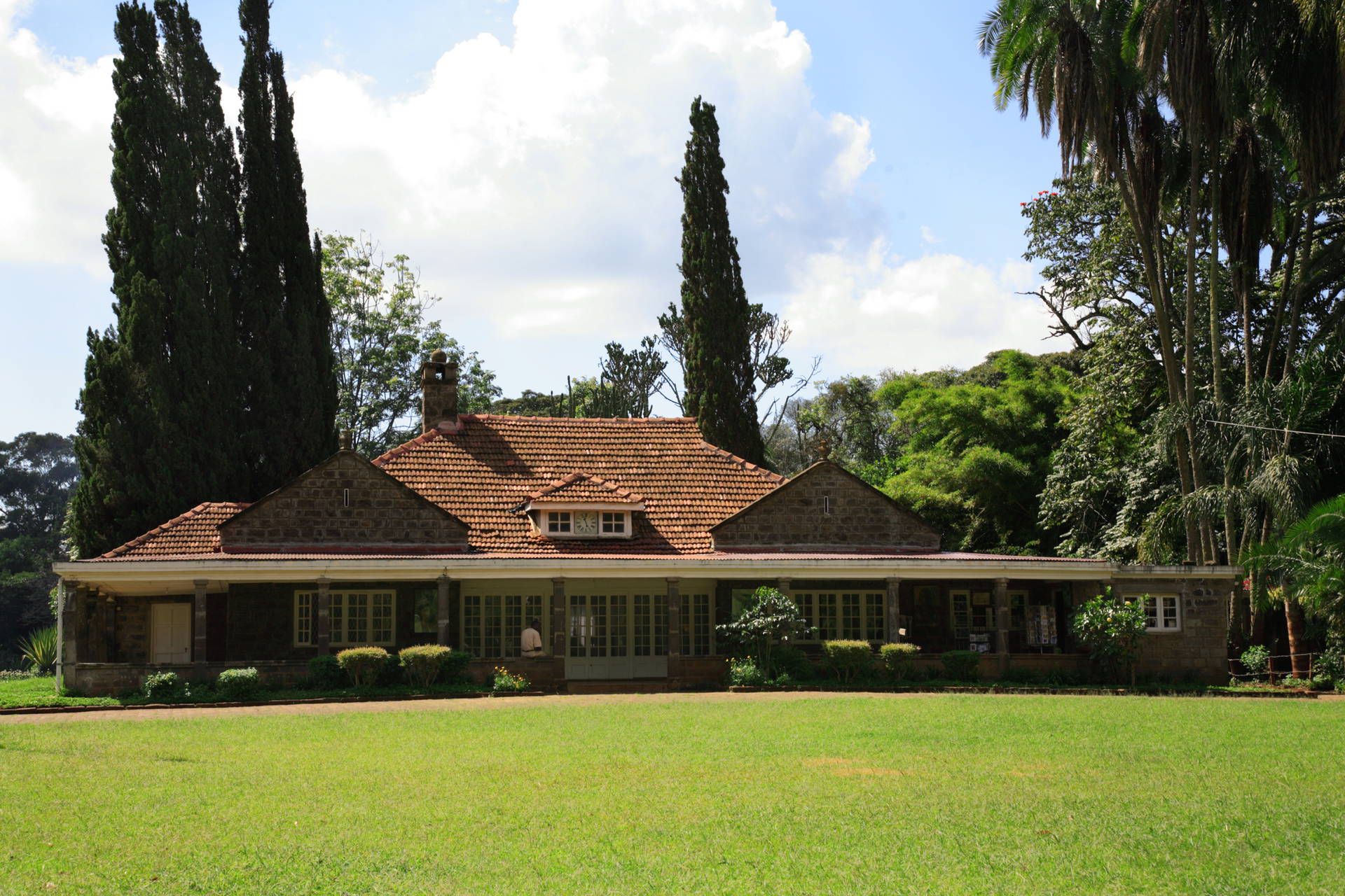 Muzeum Karen Blixen w Nairobi, Kenia. Budynek z kamienia otoczony zielonym trawnikiem.